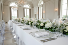 Load image into Gallery viewer, Elegant ballroom table setting with glass charger and oval-back ghost chairs
